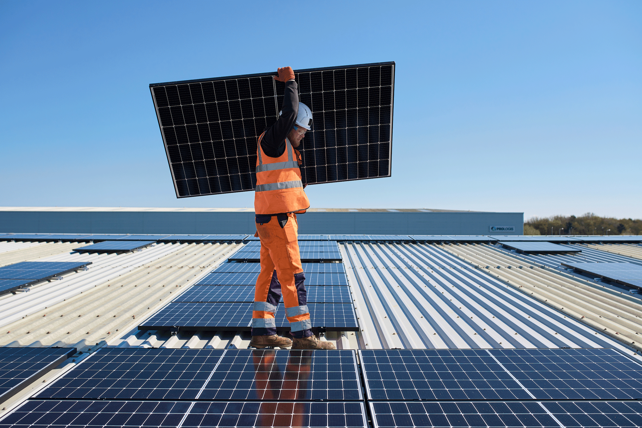 Persona che trasporta un pannello solare su un tetto Persona che trasporta un pannello solare su un tetto